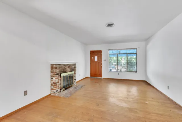 a view of an empty room with a window and a kitchen