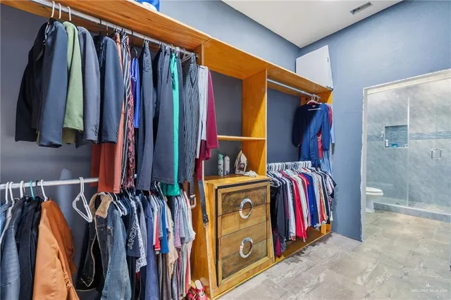 a view of walk in closet with clothes and shoes