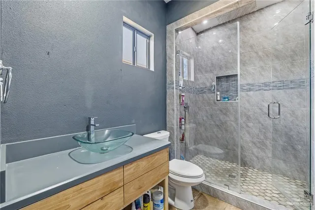 a bathroom with a granite countertop sink a toilet and shower