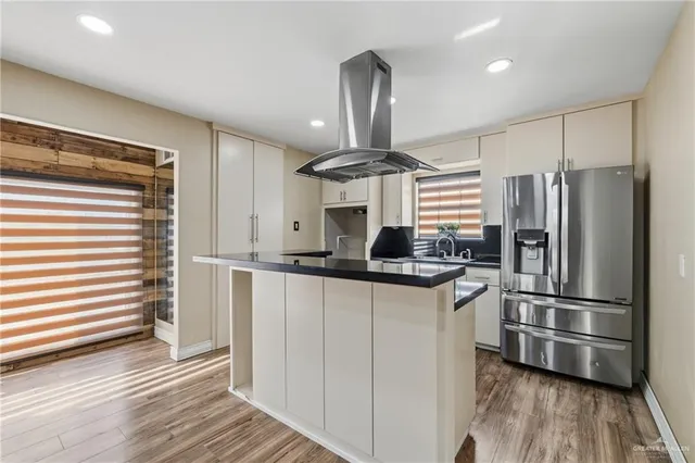 a kitchen with stainless steel appliances a refrigerator a sink and wooden floors
