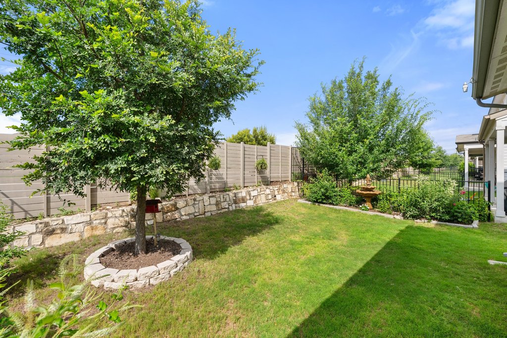7403 Travertine Spring Drive, Unit 117 Austin, TX 78744 - Photo 32 of 37 A tiered rock wall with a wooden fence adds definition to this charming backyard.