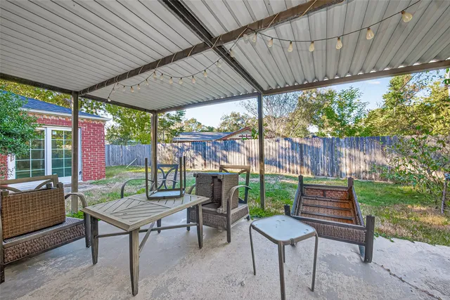 a view of a patio with a table chairs and a small yard