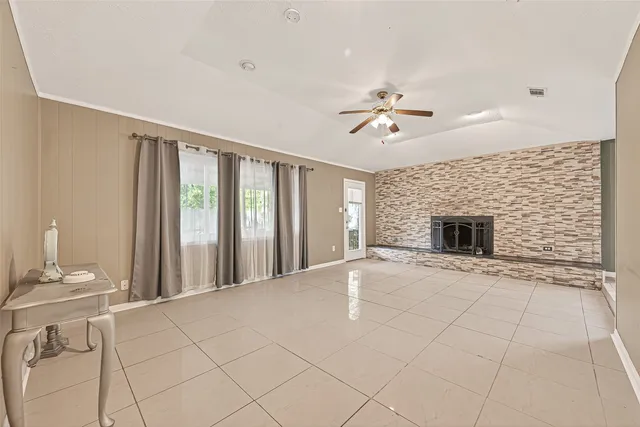 a view of an empty room with a fireplace and a chandelier fan
