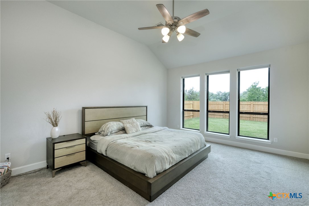 1401 Mulberry Oak Lane Georgetown, TX 78628 - Photo 13 of 30 Bedroom featuring light carpet, baseboards, vaulted ceiling, and a ceiling fan