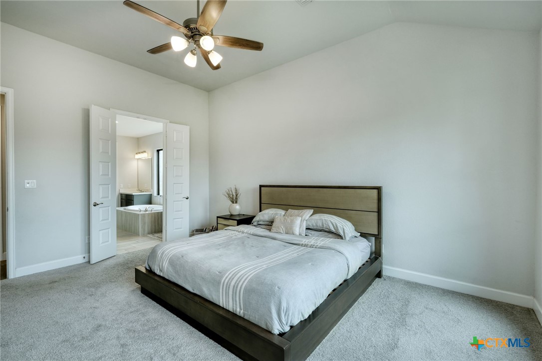 1401 Mulberry Oak Lane Georgetown, TX 78628 - Photo 14 of 30 Carpeted bedroom with baseboards, vaulted ceiling, ensuite bath, and a ceiling fan