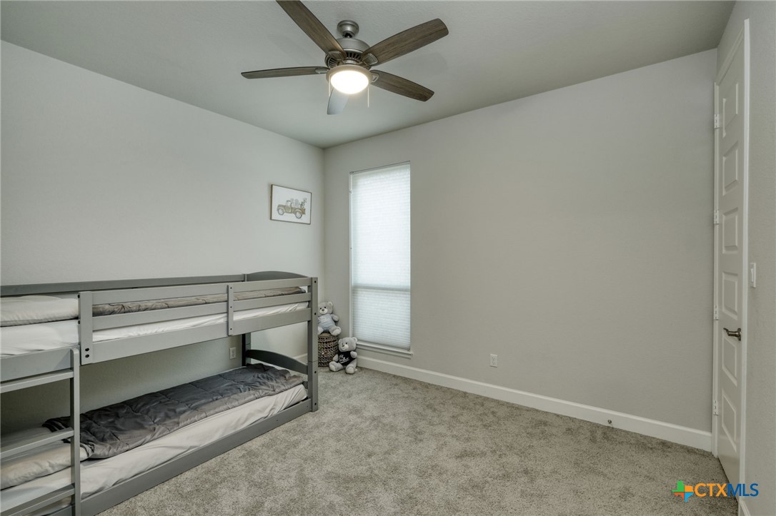 1401 Mulberry Oak Lane Georgetown, TX 78628 - Photo 18 of 30 Bedroom on the main floor featuring carpet flooring, baseboards, and ceiling fan