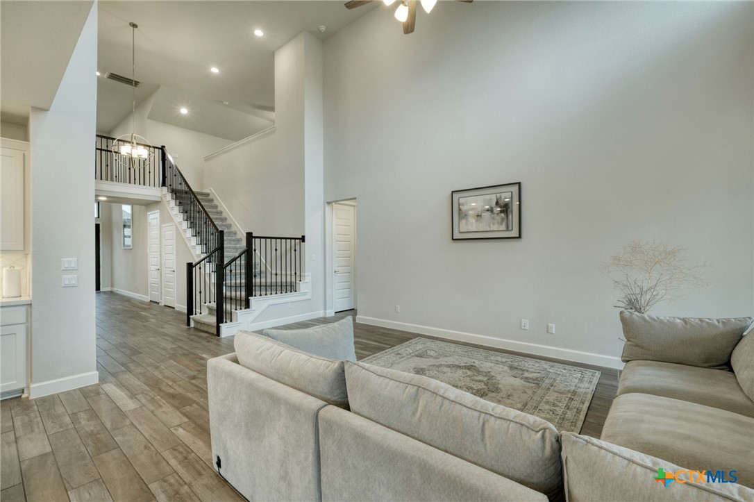 1401 Mulberry Oak Lane Georgetown, TX 78628 - Photo 8 of 30 Living room with ceiling fan, high vaulted ceiling, stairway, baseboards, and light wood-style flooring