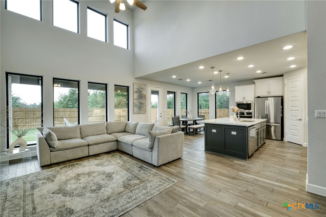 1401 Mulberry Oak Lane Georgetown, TX 78628 - Photo 9 of 30 Living area featuring light wood finished floors, a ceiling fan, a high ceiling, and recessed lighting