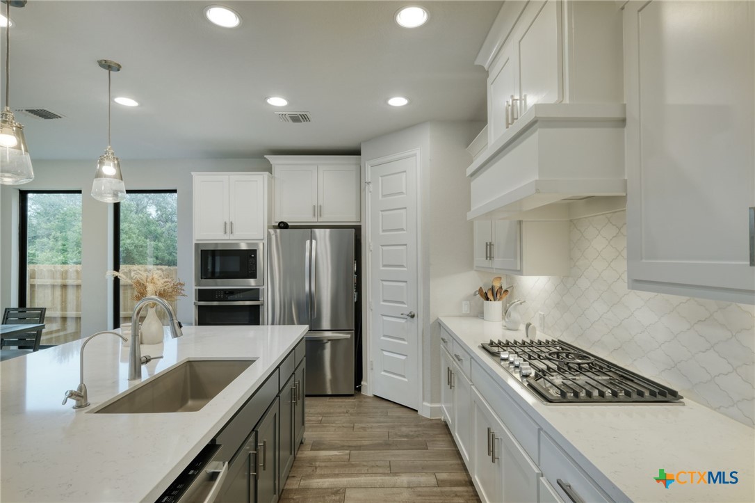 1401 Mulberry Oak Lane Georgetown, TX 78628 - Photo 10 of 30 Kitchen with stainless steel appliances, a sink, white cabinets, and light countertop