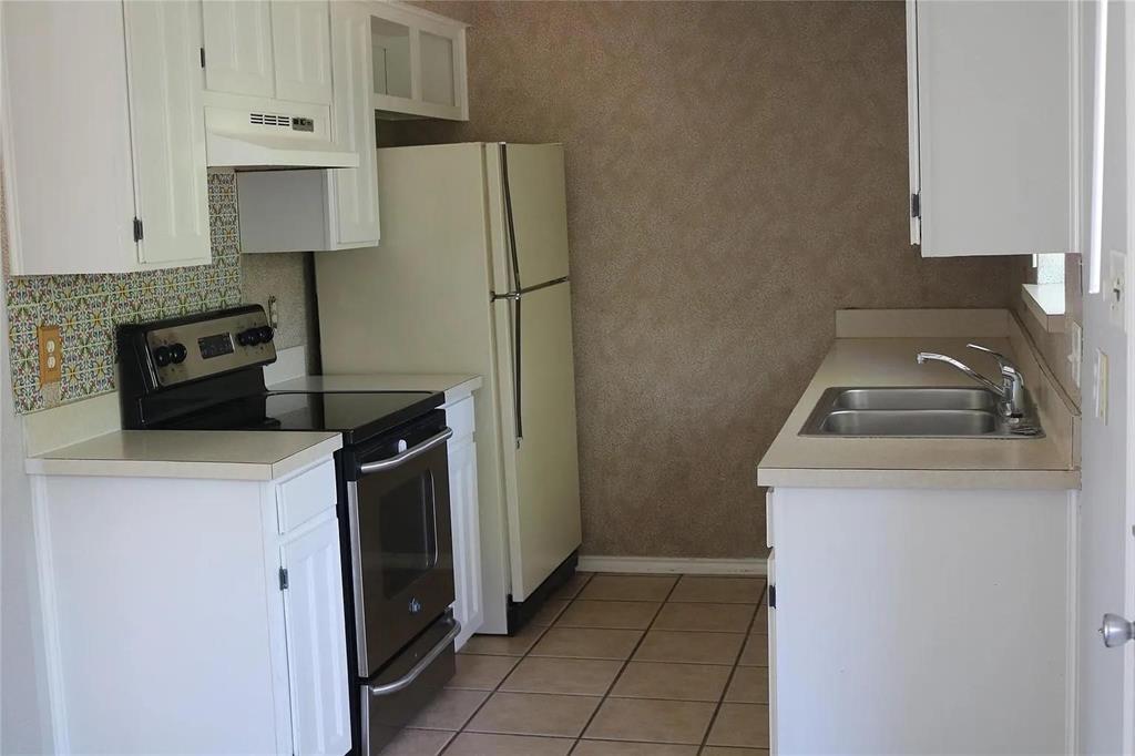 627 Cherry Lane Southlake, TX 76092 - Photo 10 of 19 Kitchen featuring stainless steel electric range oven, under cabinet range hood, white cabinetry, decorative backsplash, and light countertops
