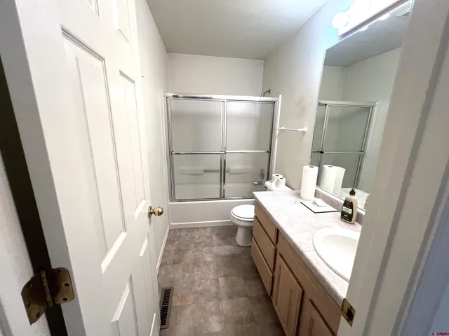 a bathroom with a sink a toilet a mirror and shower