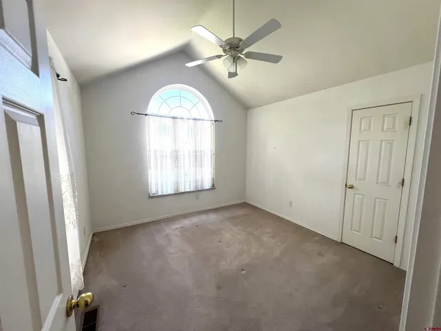 an empty room with windows and fan