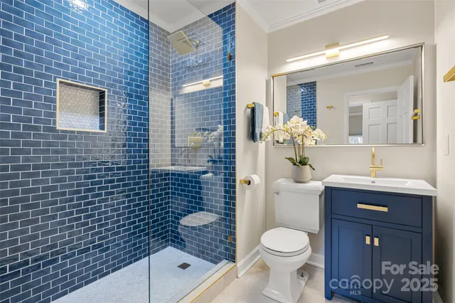 a bathroom with a granite countertop toilet a sink a mirror and shower