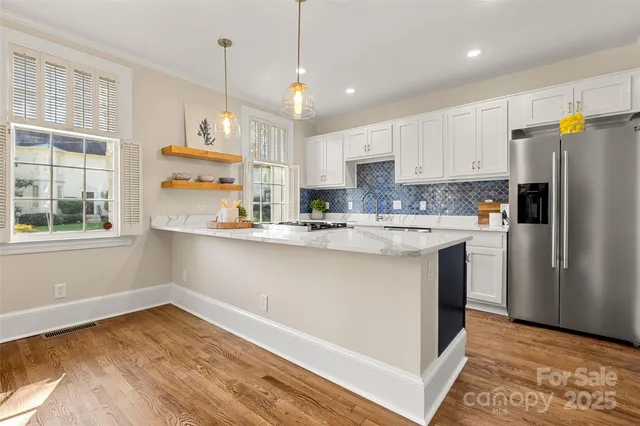 a kitchen with stainless steel appliances granite countertop a refrigerator a sink dishwasher a stove and white countertops with wooden floor