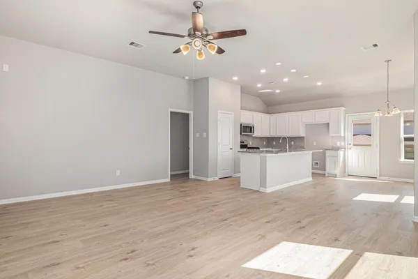 a kitchen with a sink chandelier and living room view