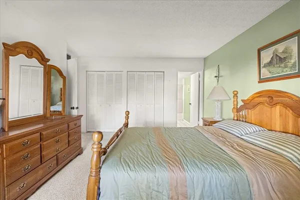a bedroom with a bed a mirror on dresser and a window
