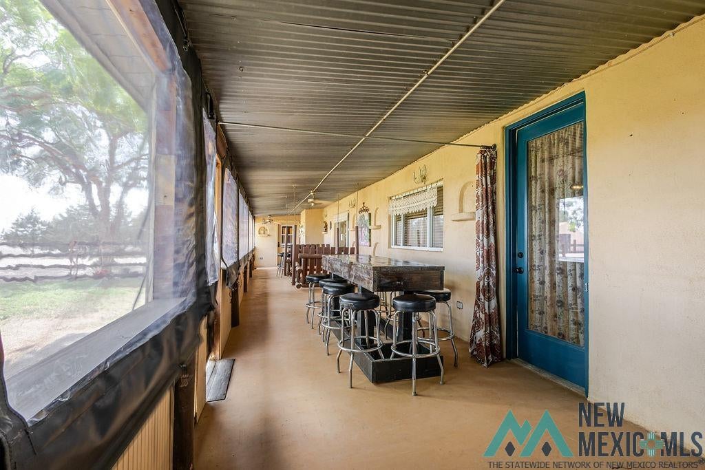 1131 Curry Road North Clovis, NM 88101 - Photo 41 of 69 Expansive covered patio featuring a corrugated metal ceiling, concrete flooring, and multiple exterior windows