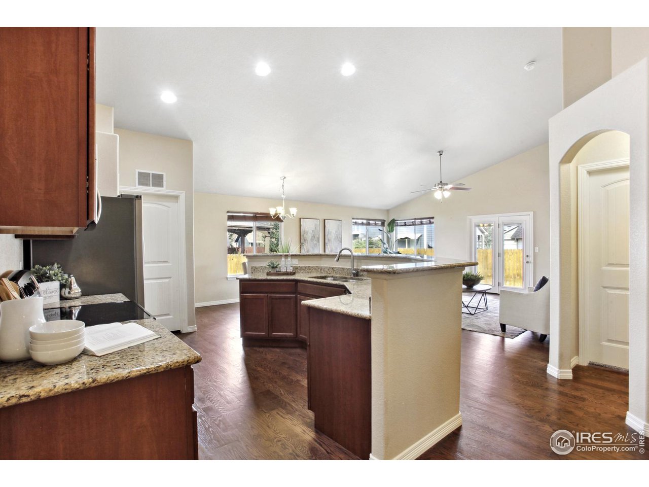 9018 Sandpiper Drive Frederick, CO 80504 - Photo 10 of 26 a kitchen with stainless steel appliances kitchen island granite countertop a refrigerator a sink a stove and oven with wooden floor