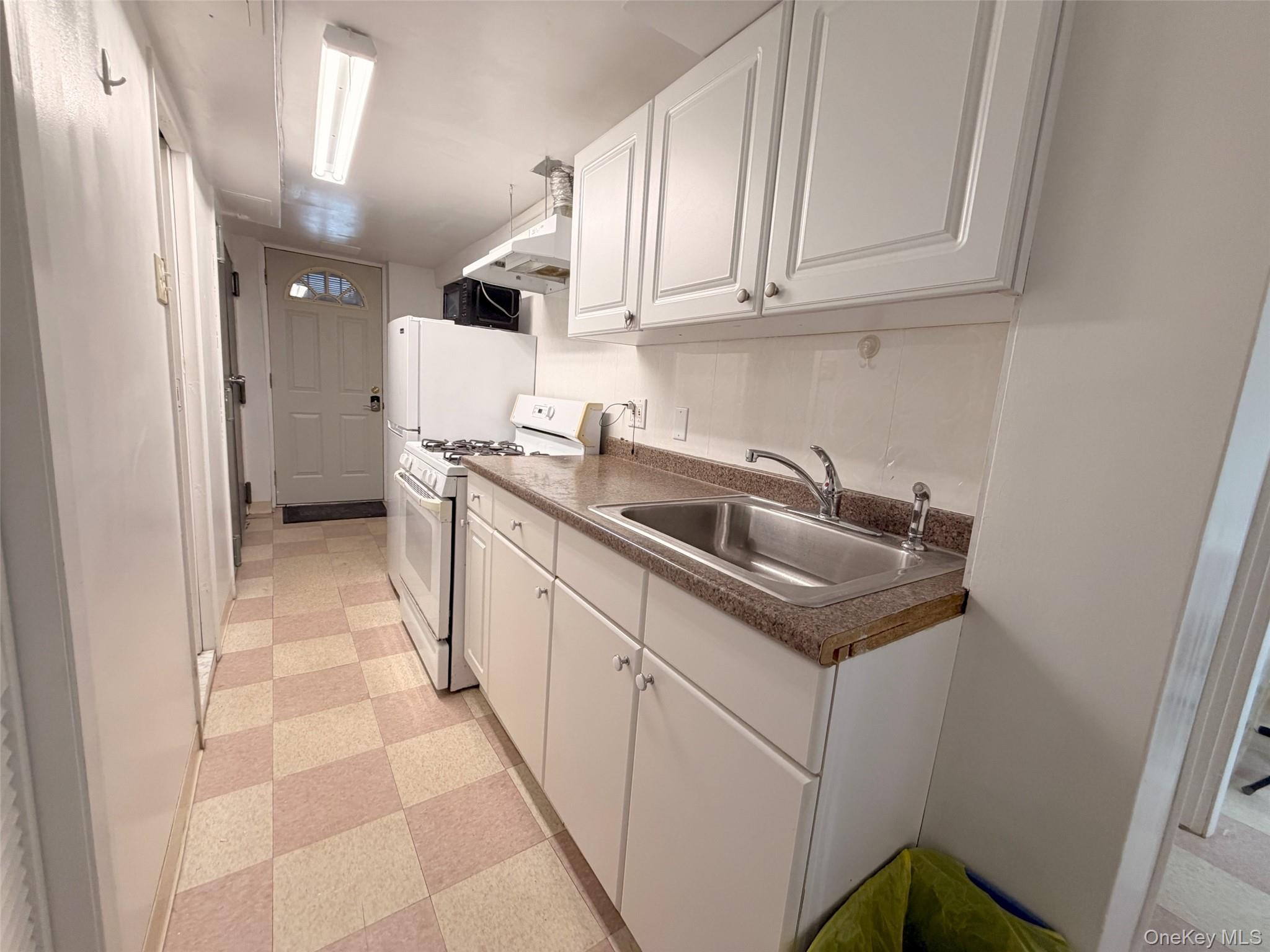153-20 77th Road, Unit 1 Queens, NY 11367 - Photo 2 of 11 Kitchen with light flooring, white cabinets, white range with gas stovetop, and black microwave