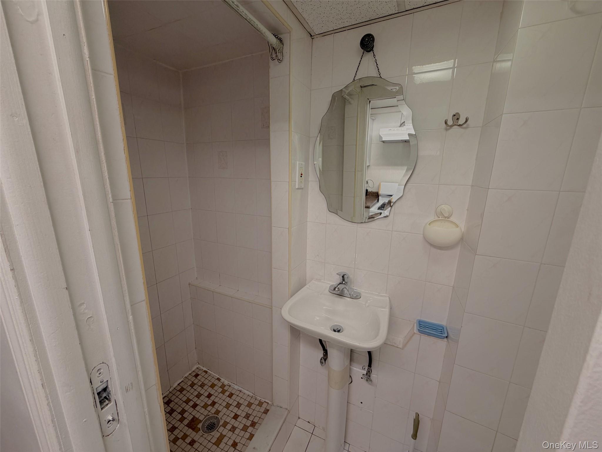153-20 77th Road, Unit 1 Queens, NY 11367 - Photo 7 of 11 Bathroom with a shower stall and tile walls