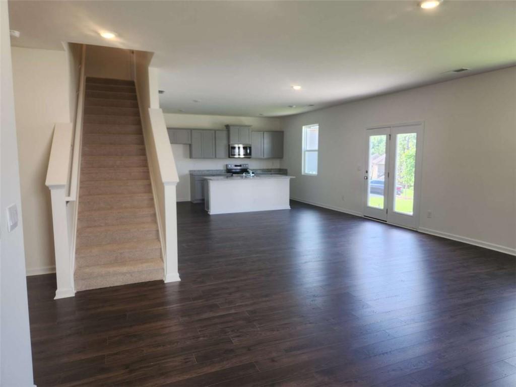 178 Aster Avenue Locust Grove, GA 30248 - Photo 17 of 36 an empty room with wooden floor and a kitchen