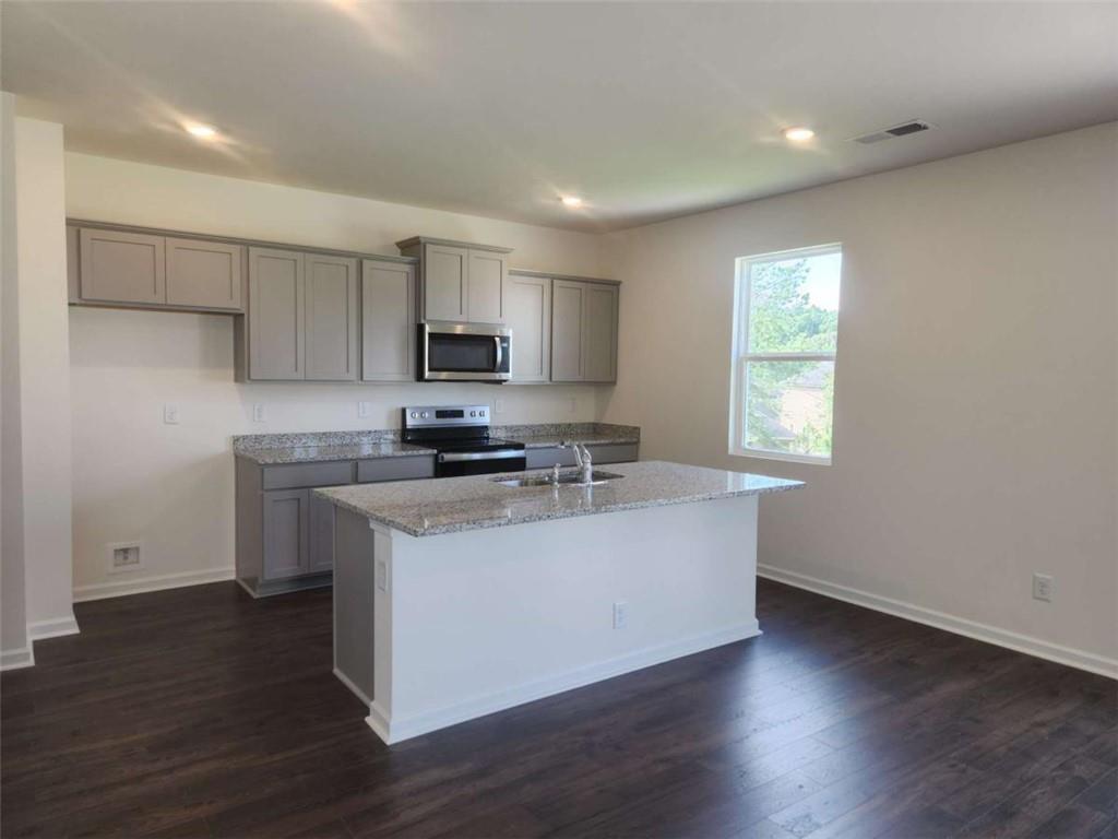178 Aster Avenue Locust Grove, GA 30248 - Photo 19 of 36 a kitchen with stainless steel appliances granite countertop a sink a stove a microwave a refrigerator a window and cabinets