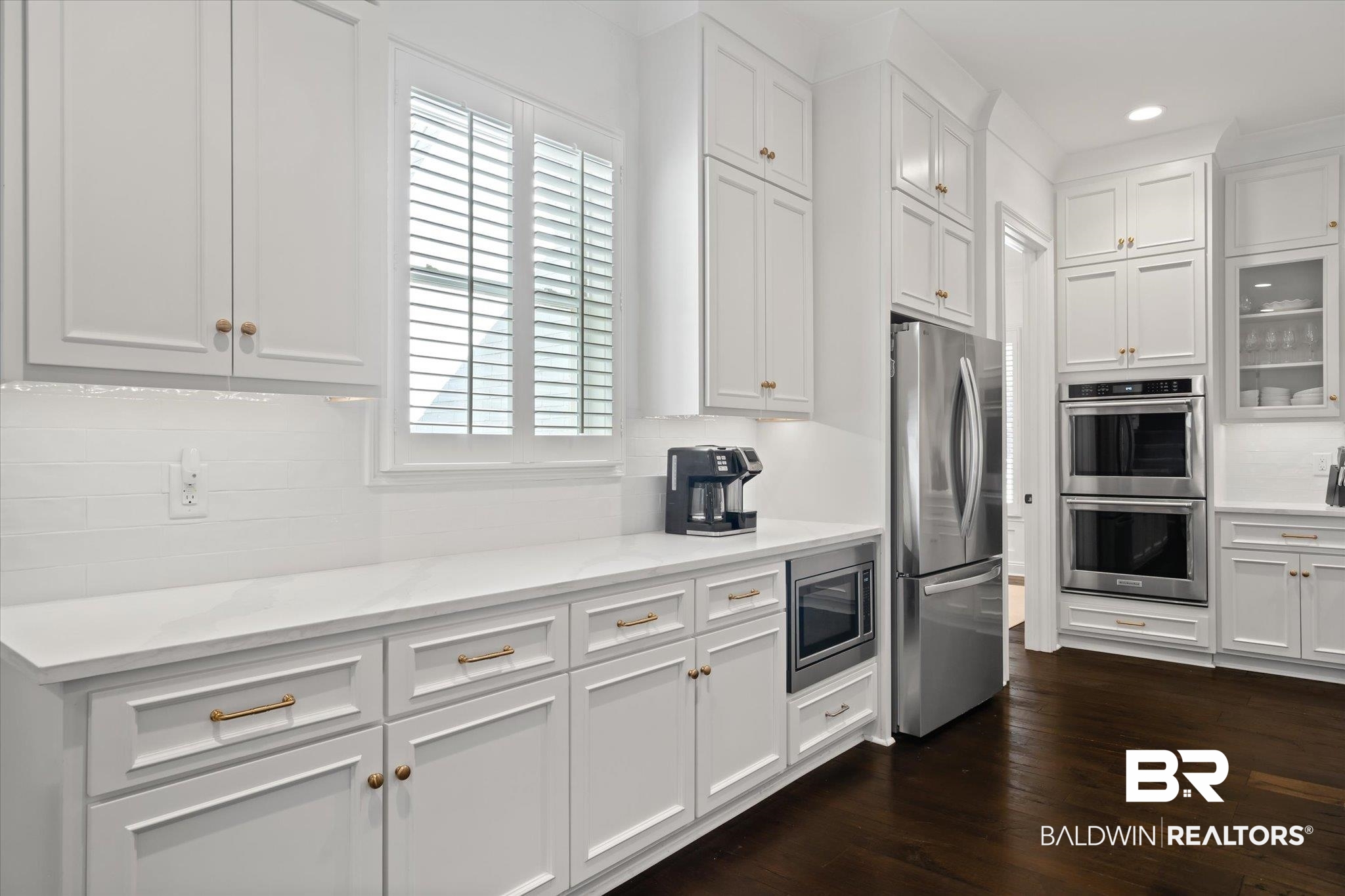 3713 Old Shell Road Mobile, AL 36608 - Photo 12 of 52 Kitchen with light stone countertops, tasteful backsplash, dark hardwood / wood-style floors, white cabinets, and appliances with stainless steel finishes