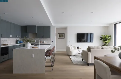 a living room with furniture a flat screen tv and kitchen view
