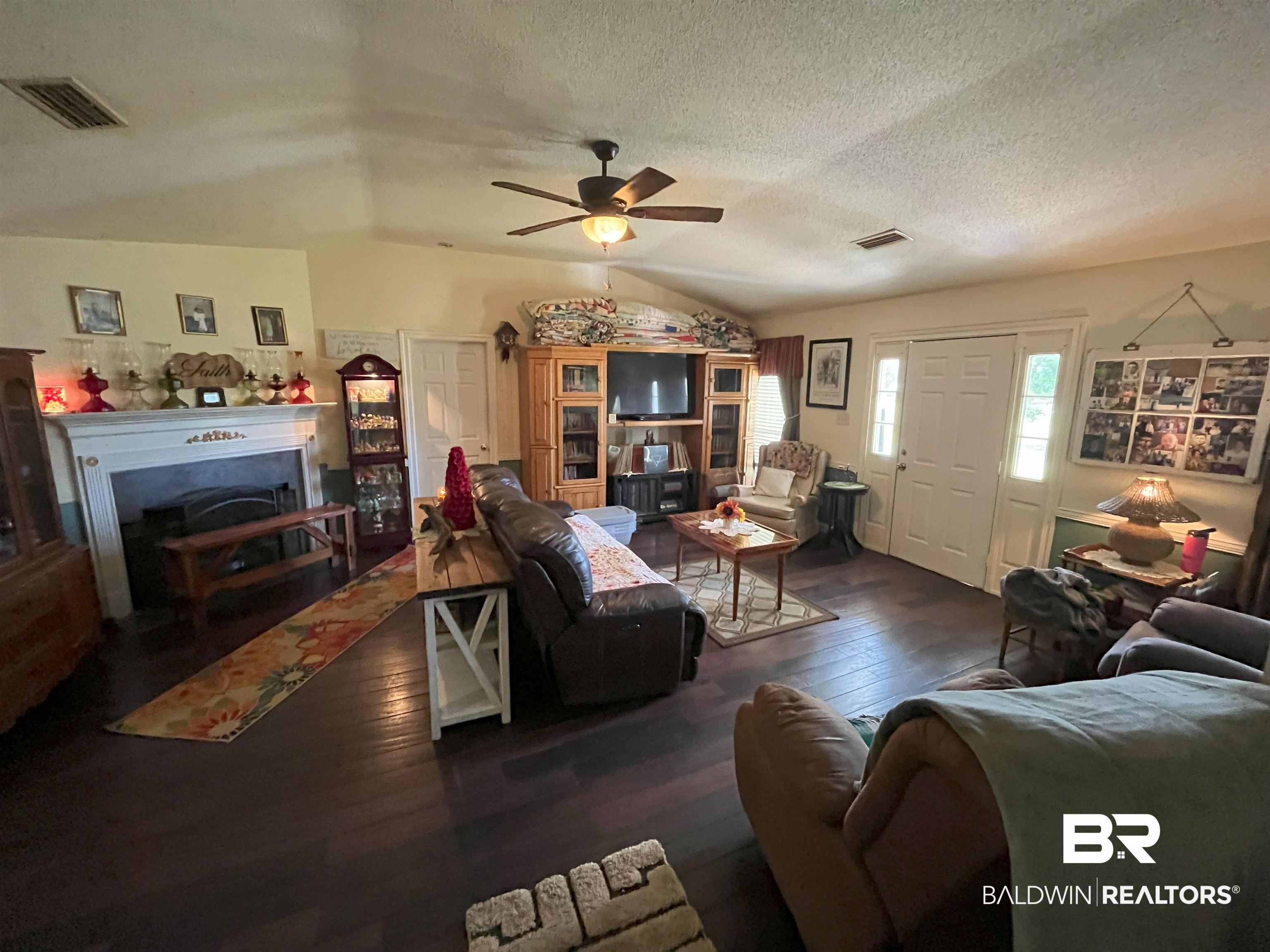7851 Highway 98 Fairhope, AL 36532 - Photo 6 of 40 Living area with lofted ceiling, wood-type flooring, a textured ceiling, ceiling fan, and a fireplace with flush hearth
