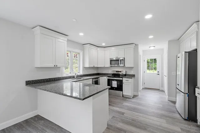 a kitchen with stainless steel appliances granite countertop a refrigerator a sink dishwasher a stove with wooden floors