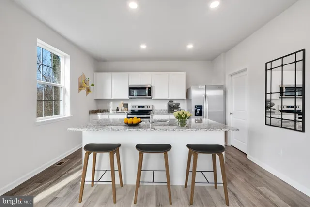 a kitchen with stainless steel appliances a dining table chairs refrigerator and sink