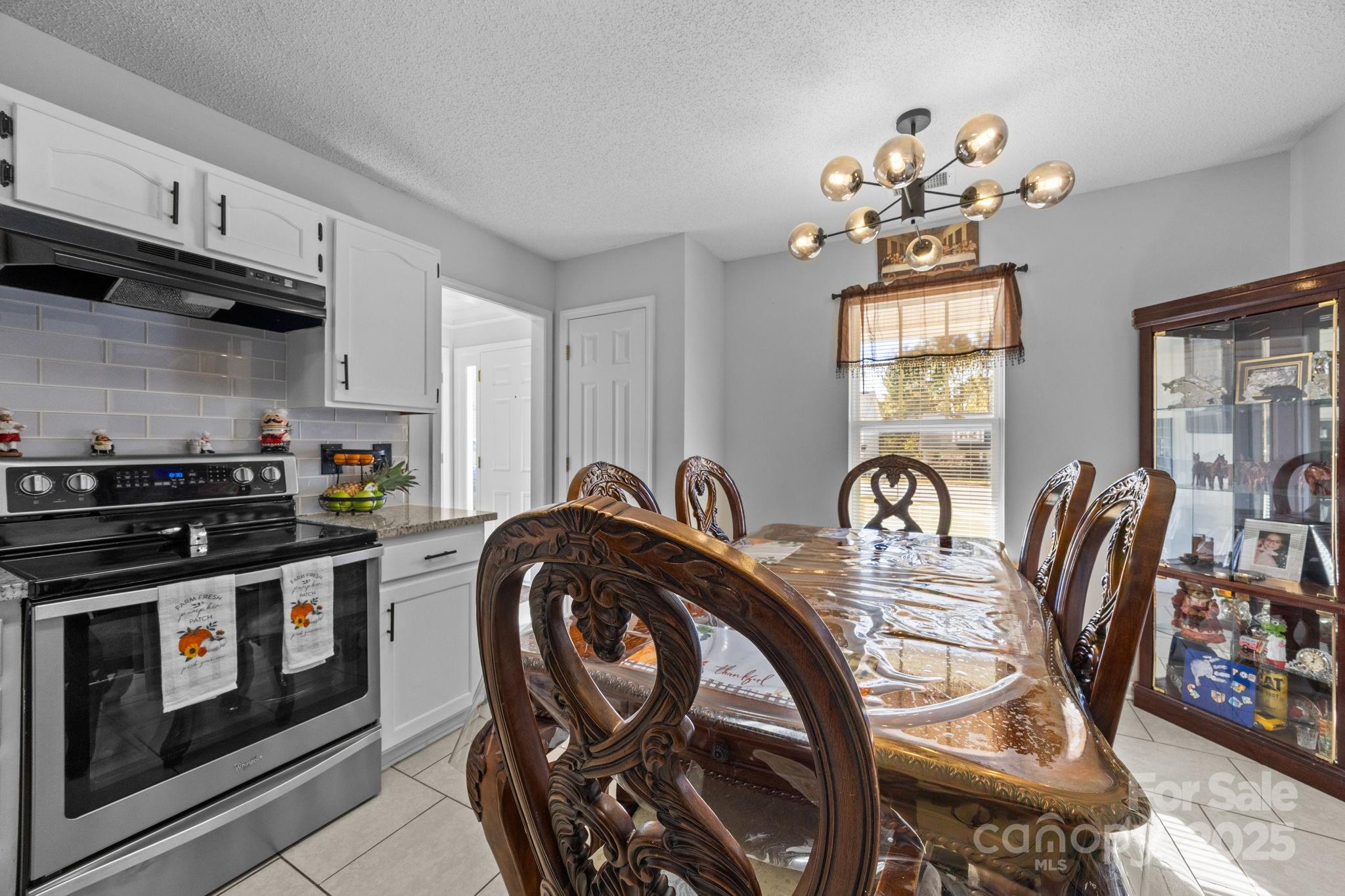 708 Raindrops Road Gastonia, NC 28054 - Photo 5 of 28 a kitchen with stainless steel appliances granite countertop a stove top oven a dining table and chairs with wooden floor