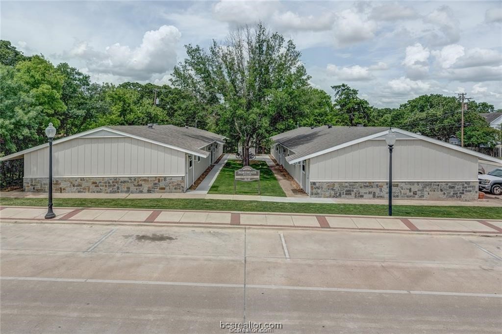 a house view with a garden and tall trees