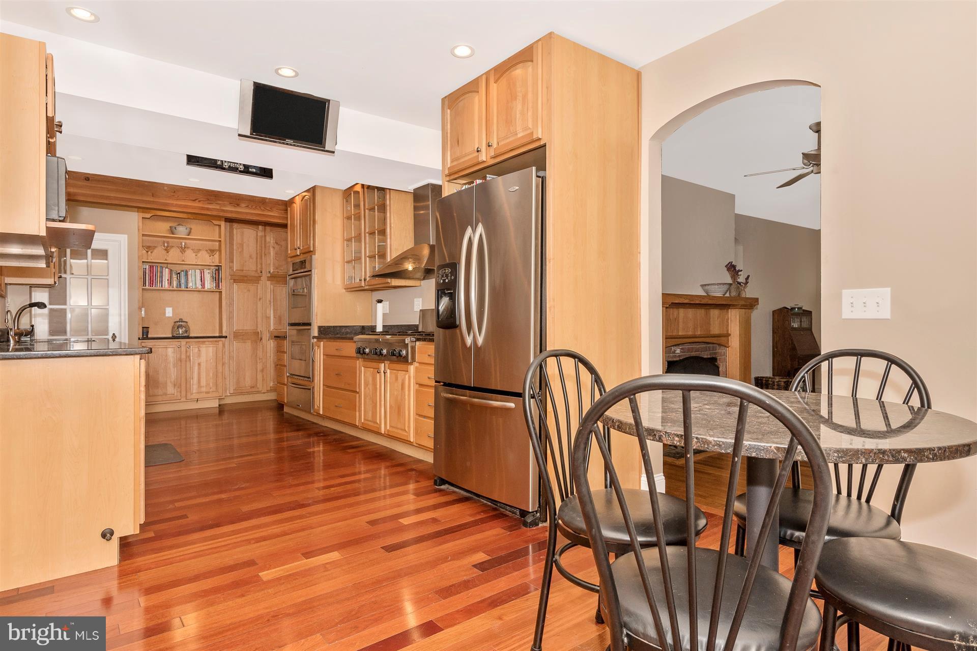 107 Sunnyside Road Silver Spring, MD 20910 - Photo 6 of 26 a kitchen with stainless steel appliances granite countertop a refrigerator a stove and a dining table with wooden floor