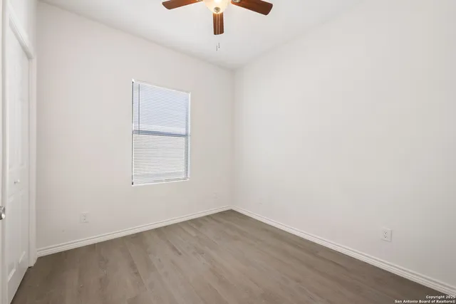 an empty room with a window and a ceiling fan