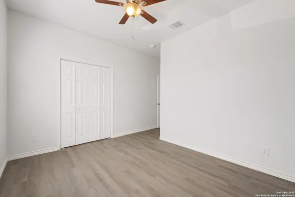 an empty room with a ceiling fan and wooden floor