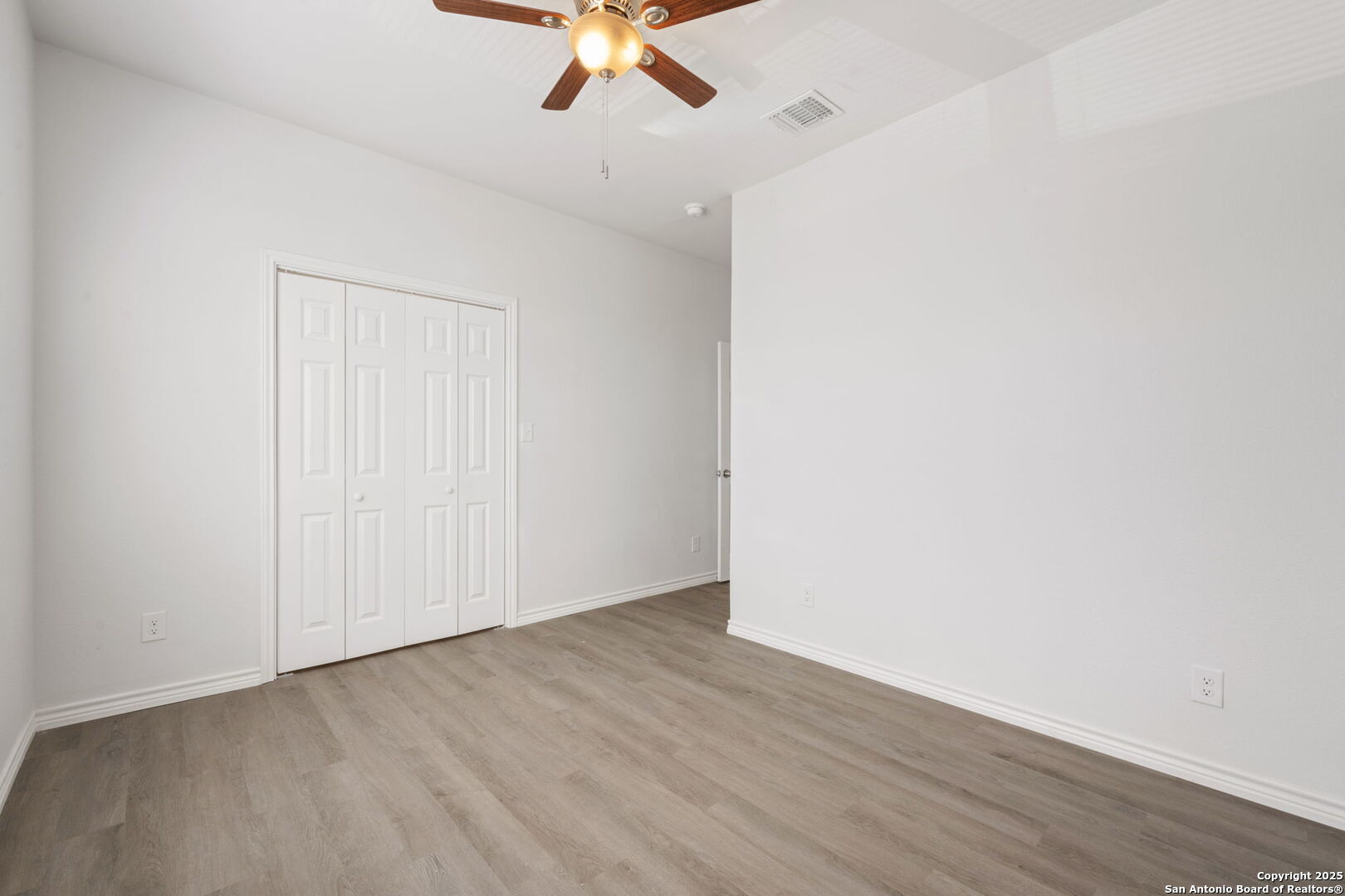 8719 Wurzbach Road, Unit 202 San Antonio, TX 78240 - Photo 9 of 18 an empty room with a ceiling fan and wooden floor