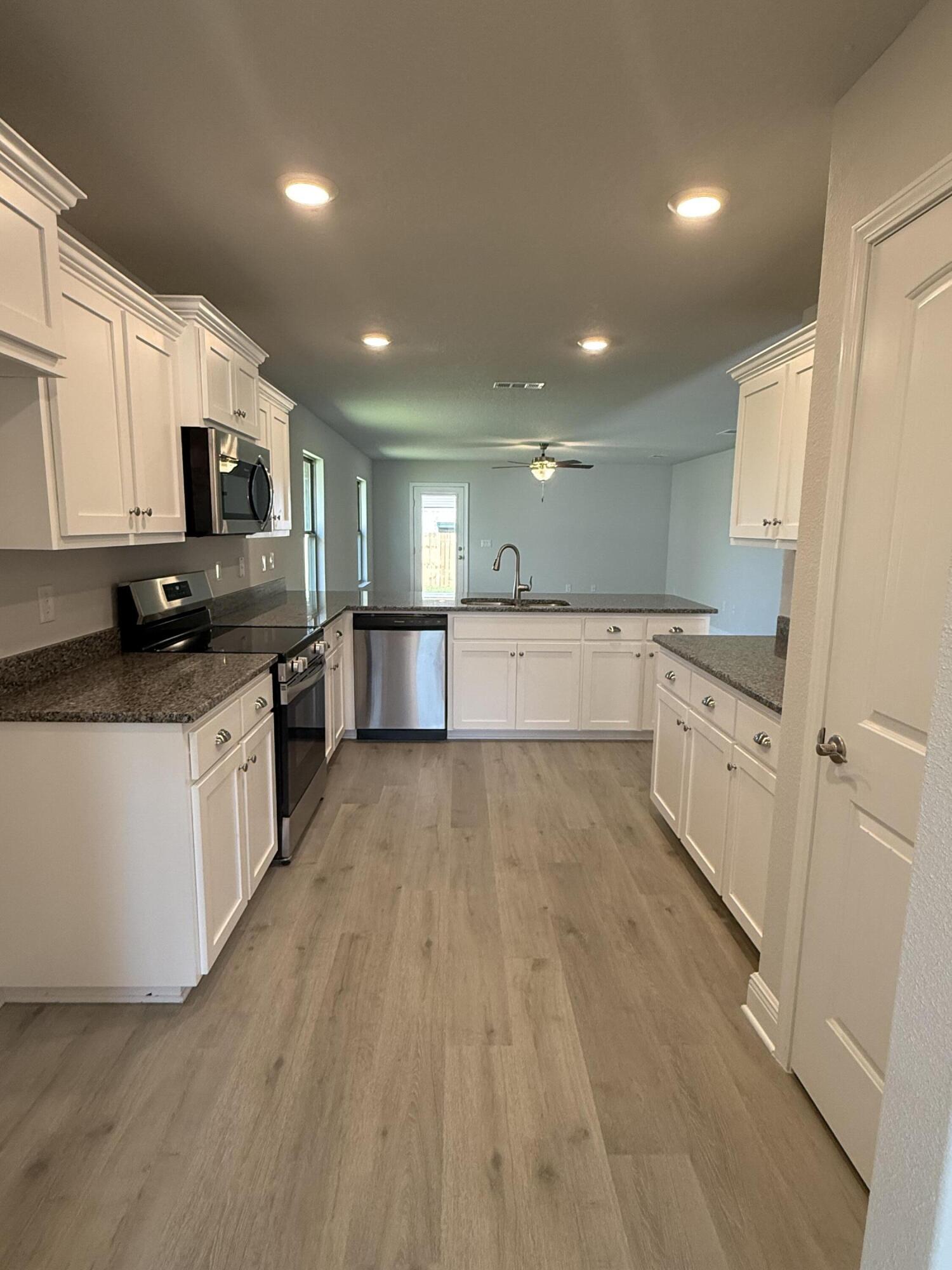 183 Ridgeway Circle Crestview, FL 32536 - Photo 12 of 28 a large kitchen with stainless steel appliances granite countertop a large stove a sink dishwasher and a refrigerator with wooden floor