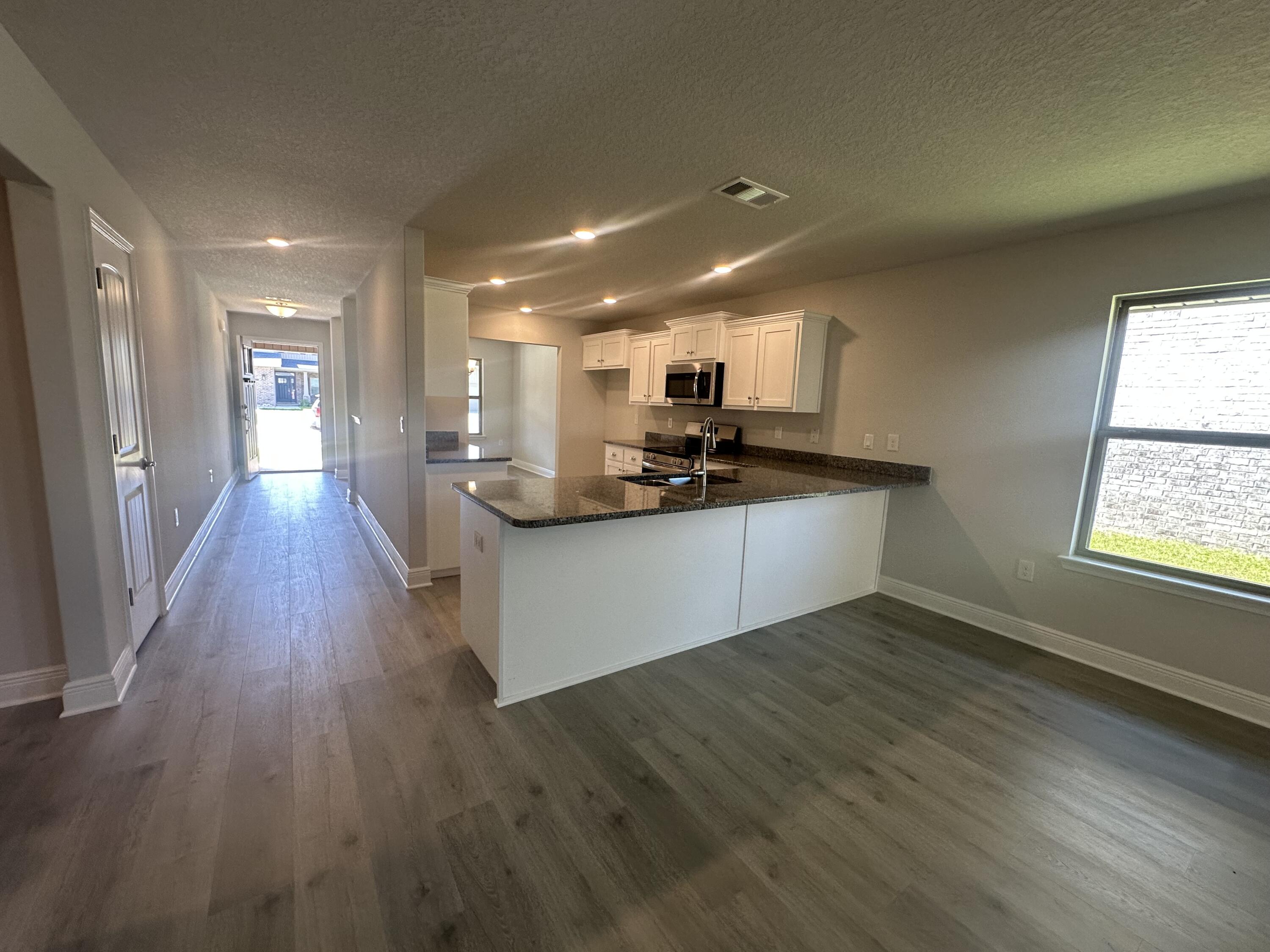 183 Ridgeway Circle Crestview, FL 32536 - Photo 10 of 28 a view of a kitchen with kitchen island a sink wooden floor and a counter top space