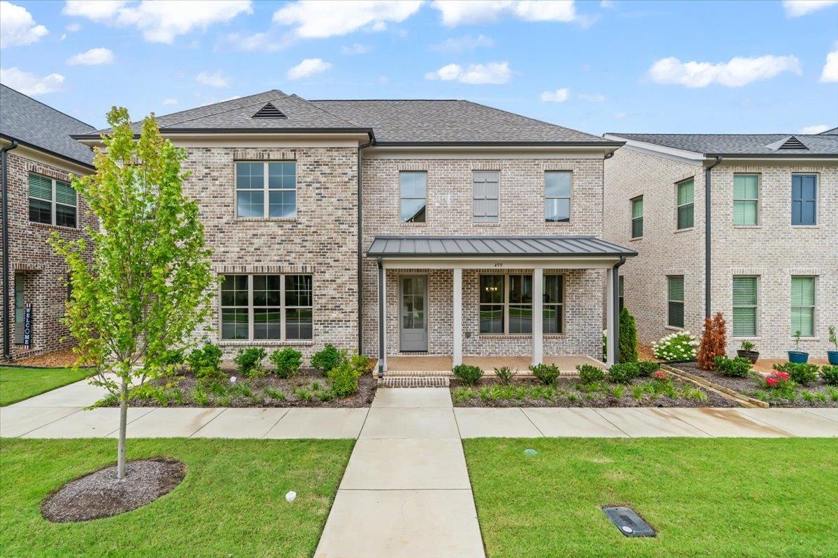 a front view of a house with a yard and potted plants