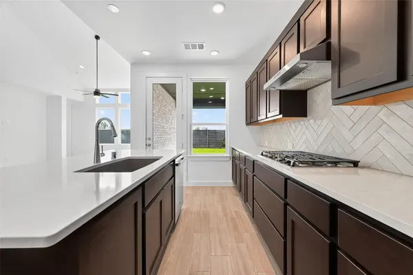 a kitchen with stainless steel appliances granite countertop a sink a stove and a wooden floors