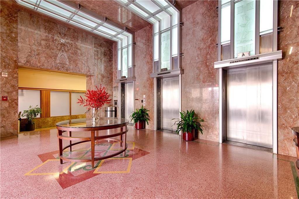 710 Colorado Street, Unit G9 Austin, TX 78701 - Photo 25 of 25 A sophisticated lobby features polished terrazzo flooring with intricate inlays, alongside sleek elevators and marble-clad walls.