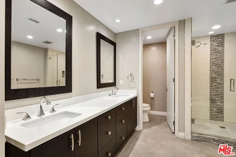 a bathroom with a double vanity sink mirror and shower