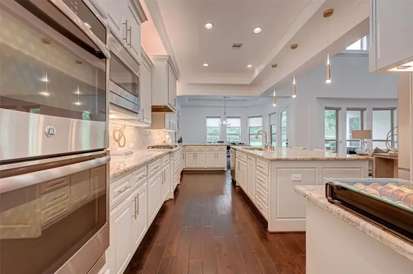 a large white kitchen with kitchen island a stove a sink a refrigerator and cabinets