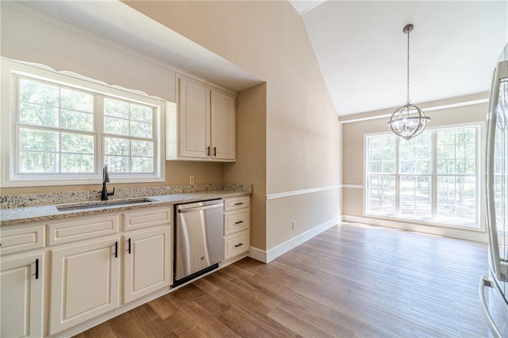 246 Azalea Farms Road Social Circle, GA 30025 - Photo 9 of 27 a open kitchen with granite countertop a stove a sink and white cabinets with wooden floor next to windows