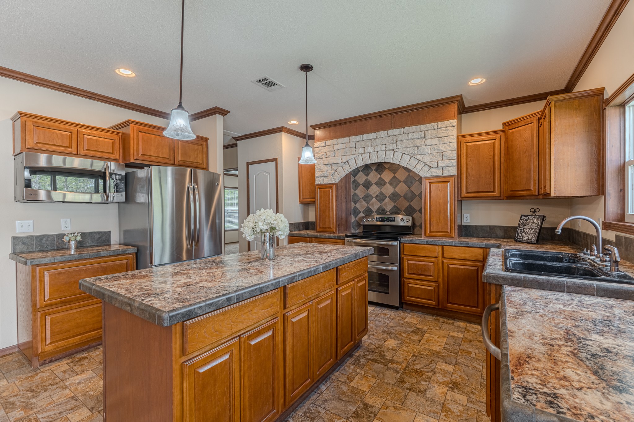 115 Canadian Drive Trinity, TX 75862 - Photo 9 of 42 Stainless steel appliances. It includes a built-in microwave, a double sink, and a decorative stone backsplash, offering a cozy and functional space.