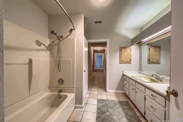 a spacious bathroom with a granite countertop sink a mirror a bathtub and shower