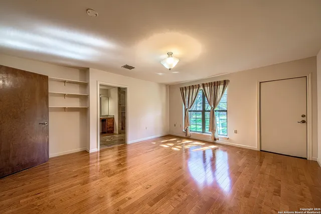 a view of an empty room with a window and wooden floor