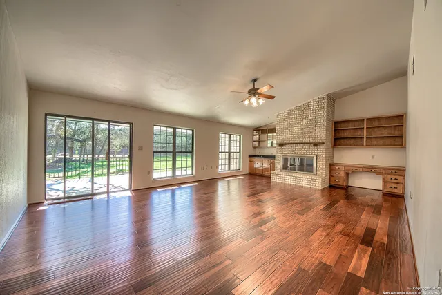 a view of empty room with wooden floor and fireplace