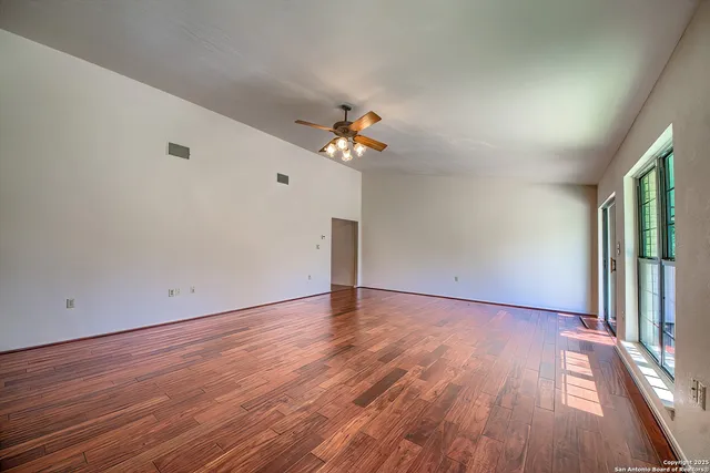 a view of a room with wooden floor and a ceiling fan